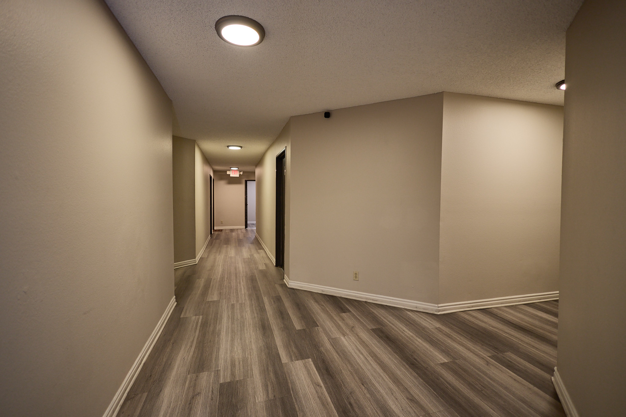 A long hallway with wood flooring and white walls.